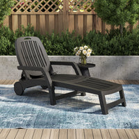 Person reclining on black lounge chair in backyard on sunny day